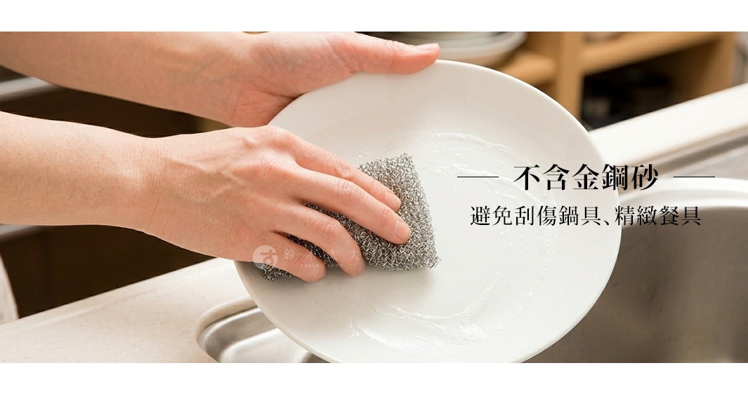 一雙手正拿著一塊細緻的金屬網狀菜瓜布，輕柔地刷洗白色陶瓷盤子，圖片右側文字標示此菜瓜布不含金鋼砂成分，能有效清潔而不刮傷精緻餐具或鍋具，展現溫和且高效的清潔方式。