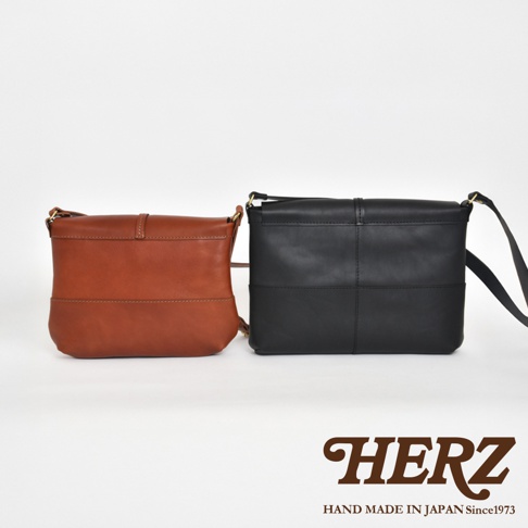 日本HERZ品牌，兩個皮革馬鞍包，一個為棕色，一個為黑色，兩個包包的細節處都有縫線設計，近景拍攝。