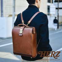 職人手作皮革杜勒斯商務後背包，經典棕色，採用厚實皮革材質，配有金色鎖扣及金屬配件，設計簡約且具復古感，適合商務場合。