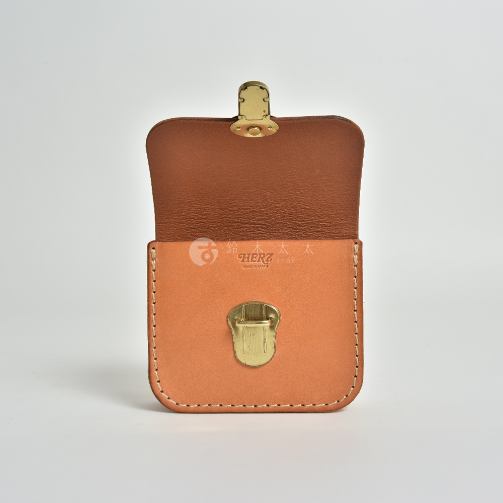 一咖淺棕色皮革製作的經典腰包，包身結構方正，正面配有金色金屬鎖扣，翻蓋內側為深棕色皮革。