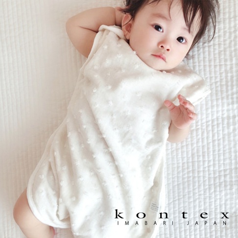 一位穿著白色水玉點點無撚紗質透氣寶寶防踢被心的嬰兒。