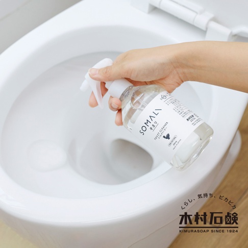 手持透明噴霧瓶，瓶身標示 SOMALI 泡沫式馬桶清潔劑，正對著白色馬桶噴灑。