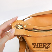 職人手作的厚實皮革單肩波士頓包，特寫展示了金屬拉鍊、皮革拉頭和縫線細節，呈現天然皮革的溫潤色澤。