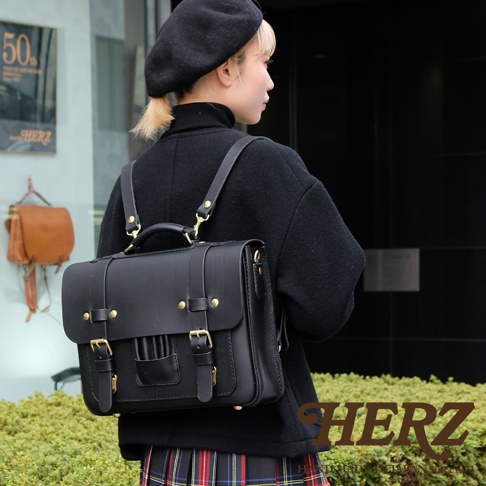 黑色皮革三用學生包，配有金色金屬扣和可拆卸肩帶，可作背包、側背包或手提包使用。