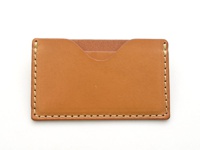 職人手作皮革卡片夾，淺棕色牛皮材質，以米白色線縫合邊緣，正面有一個弧形開口設計。