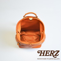 職人手作皮革輕旅行後背包 R-144，展示棕褐色皮革材質，包包開口朝上，內部結構清晰可見，帶有提把和金屬釦環，底部有铆釘裝飾。