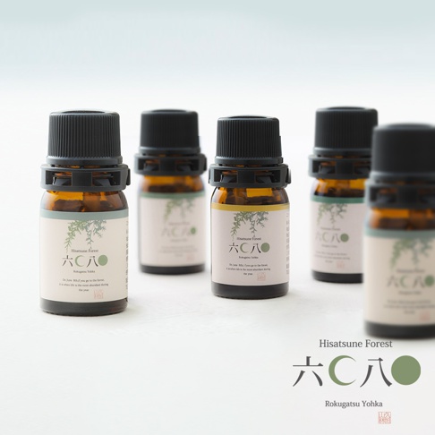 五瓶琥珀色玻璃精油瓶，配有黑色螺旋瓶蓋，瓶身貼有淺綠色標籤，印有日文與英文說明及樹枝圖案。