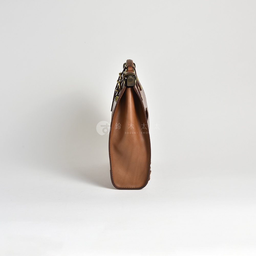 一個側面的棕色復古皮革後背包，配有金屬口金和皮帶扣。