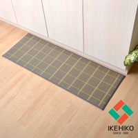 藺草編織的長方形廚房地墊，表面有綠色格紋，深藍色滾邊，置於淺木紋地板上，背景為白色櫥櫃。