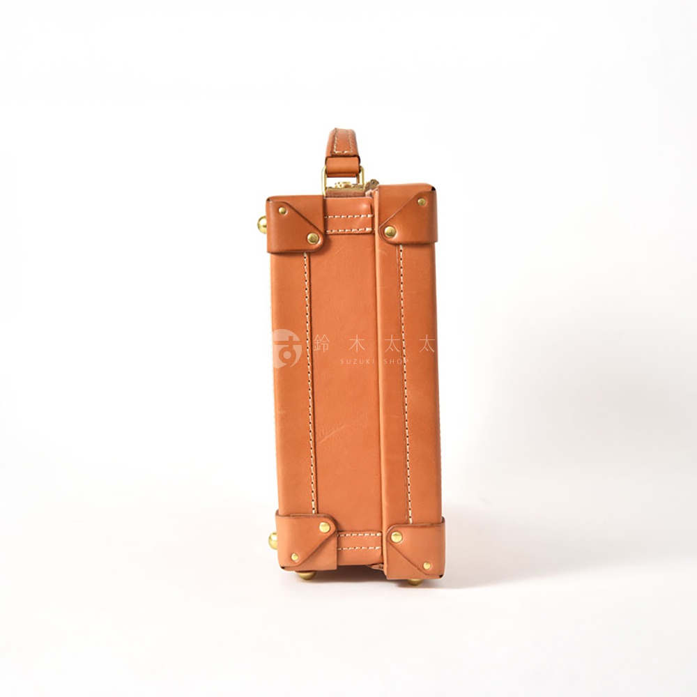 職人手作的棕褐色皮革英倫風便攜手提行李箱，箱體以皮革包裹，搭配金屬邊角和鉚釘，頂部有提把，整體風格經典復古。