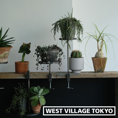 鐵製可夾式小物高低桌 (一組2入) S，展示於木質層架上，夾具為金屬黑色，支架為銀色金屬，承載著不同盆栽植物，包括仙人掌、吊蘭等，背景為白色牆壁。