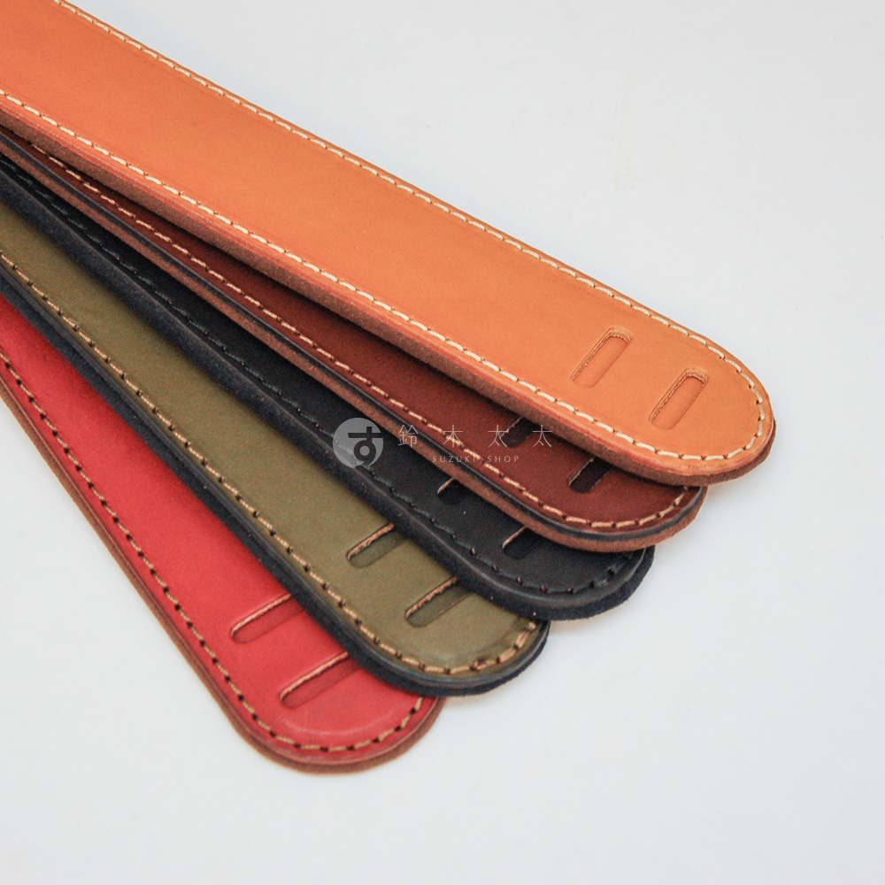 職人手作皮革Big肩墊，展示了紅、綠、黑、棕、橘五種顏色，皮革表面有縫線和兩個長方形切口。