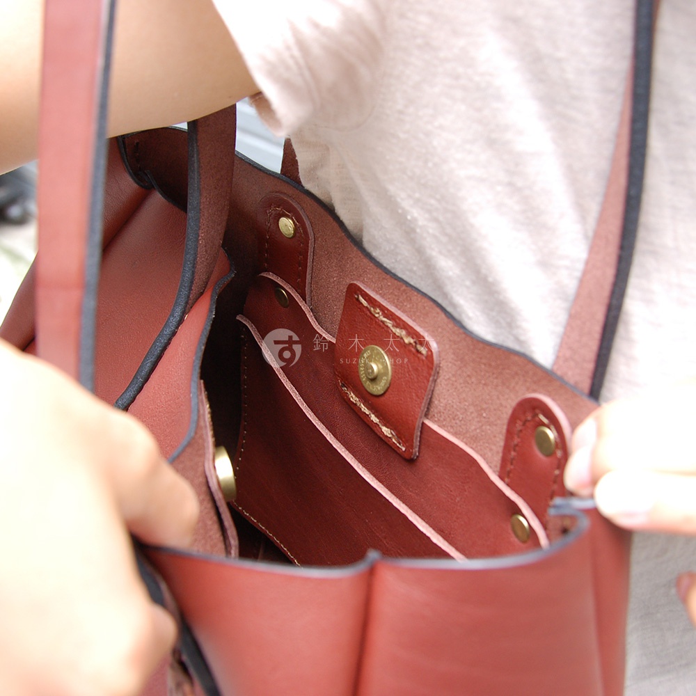 職人手作皮革仕女托特包，酒紅色，展示包內置物隔層與金屬釦細節。