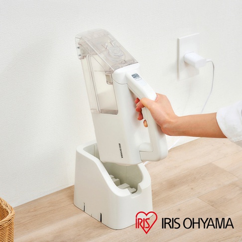 白色隨心無線織物清潔機，配有透明水箱和充電底座，置於木質地板和白色牆壁旁。