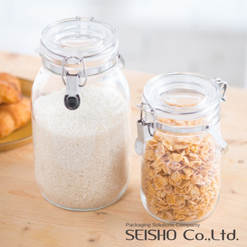 兩個透明玻璃密封儲物瓶，左瓶裝滿白色米粒，右瓶裝滿金黃色玉米片，均配有銀色金屬鎖扣和透明密封蓋。
