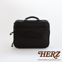 黑色皮革兩用商務公事包，方形設計，頂部有提把，正面有拉鍊夾層，側面有拉鍊開口，中央有品牌標誌。