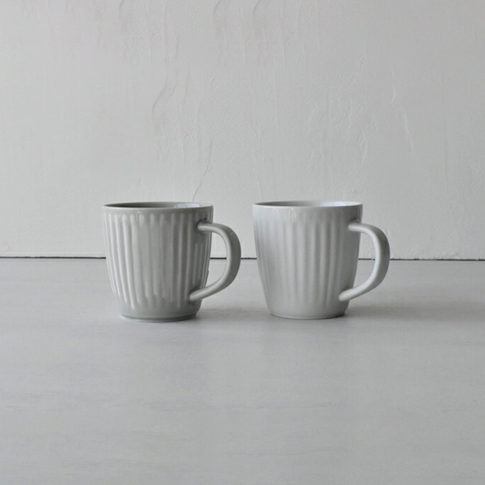 兩件式波佐見燒馬克杯，一個為淺灰色，另一個為白色，皆為直條紋設計，帶有圓弧形杯柄，材質為陶瓷。