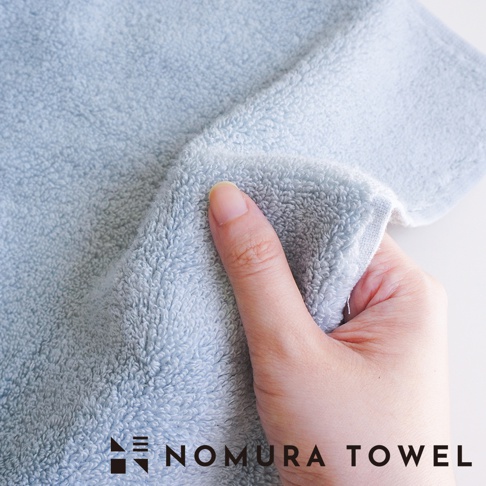 野村毛巾 LOGO 和文字「NOMURA TOWEL」標誌在藍色毛巾上。
