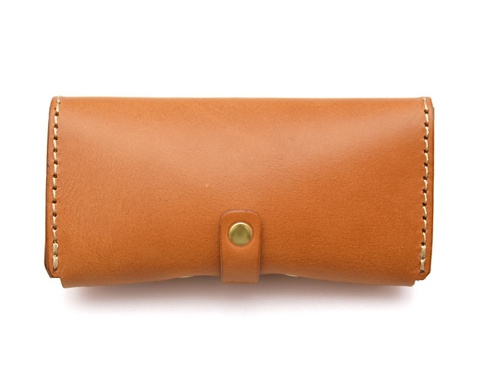 棕色皮革製作的眼鏡收納盒，附有金色按扣和車縫細節，設計簡潔，適合收納眼鏡。