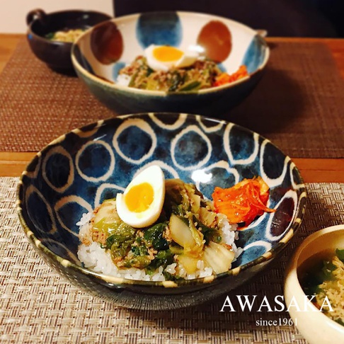 兩個筆青釉繪寬口丼碗，碗內盛有白飯、炒蔬菜、肉末及半顆水煮蛋，碗外緣有藍色繪製的圓形紋飾。