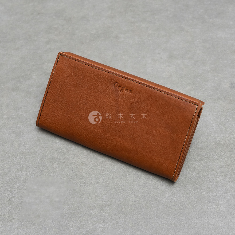 這款日本 HERZ 職人手作皮革 Organ 長夾採用簡約的棕色皮革製成，表面刻有 Organ 字樣與鈴木太太標誌，外觀呈現細膩的皮質紋理，邊緣縫線工整，整體散發出質感厚實的手作風格。