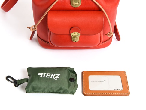 職人手作皮革經典迷你後背包，採用亮橘色皮革，附有翻蓋口袋與金屬釦環，側邊有繫繩。另有軍綠色摺疊收納袋，以及淺棕色皮革證件夾。