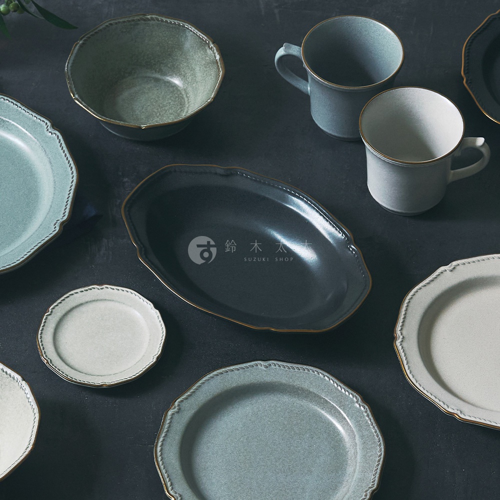 Stitch 美濃燒金彩浮雕橢圓深盤 (共2色)，圖片包含多種不同款式和顏色的盤子和杯子，像是藍綠色、灰色、白色等，部分盤子帶有金色的浮雕邊緣，中間有一行日文和SUZUKI SHOP字樣。