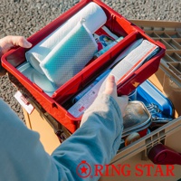 紅色塑膠工具箱內裝有捲起的白色紙巾、藍色網狀布料、餐具和一些其他物品，箱子放在一個淺棕色的收納盒中。