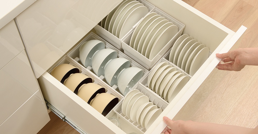 抽屜式餐碗收納架整齊擺放著白色和米色的碗盤，清晰的隔層讓餐具一目了然。