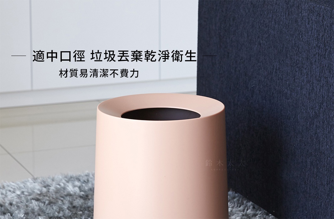 一個圓形、淺粉色的家用垃圾桶，容量11.4L，具有寬大開口，材質光滑易清潔，置於灰色地毯上，背景為深藍色方塊。