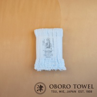 淡藍色三層紗純棉掛脖毛巾，帶有細緻的流蘇邊緣，包裝上印有女性運動圖案與日文說明。