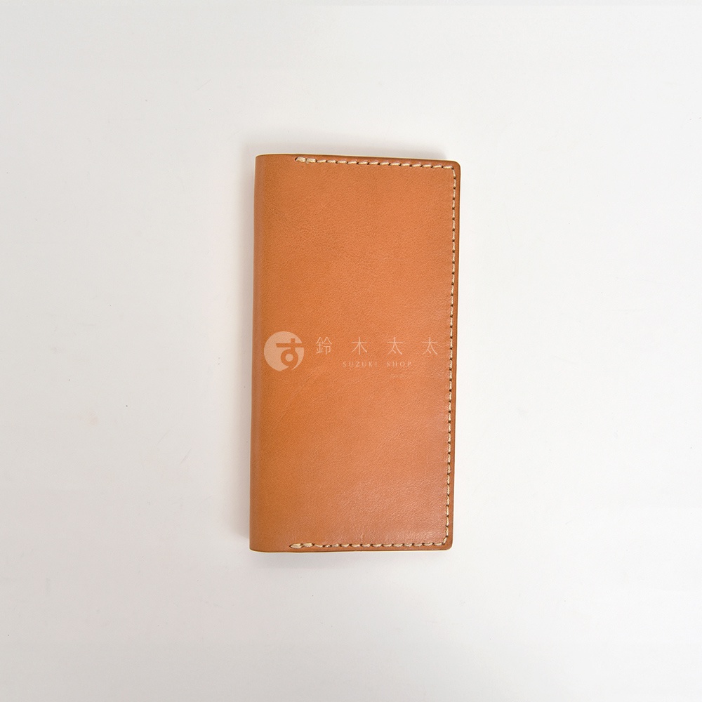 淺棕色職人手作皮革旅行記事本書套，表面光滑，以米白色縫線包邊，右側印有「鈴木太太 SUZUKI SHOP」的白色Logo。