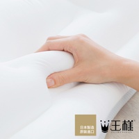 左手輕壓白色極夢枕，枕面呈現柔軟的凹陷，質感光滑。枕頭邊緣有淺灰色網狀織物。右下角有「日本製造 原裝進口」及「王樣 OSAMASERIES」的品牌標誌。