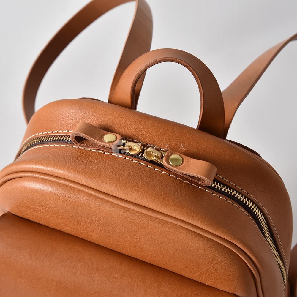 職人手作皮革迷你後背包，採用棕色皮革材質，配有金色拉鍊和固定扣，以及簡潔的車縫線。