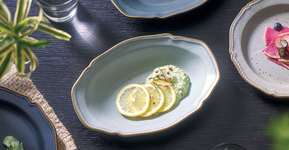 Aito Stitch 系列美濃燒金彩浮雕橢圓深盤，盛裝著綠色的醬料，盤緣擺放三片檸檬切片，盤子右側的另一盤盛有蘿蔔和藍莓。