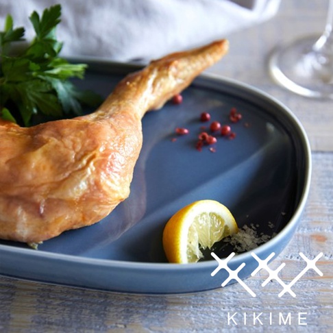 藍色波佐見燒橢圓主菜盤，盤中盛有烤雞腿、檸檬片、粉紅胡椒粒及香草。