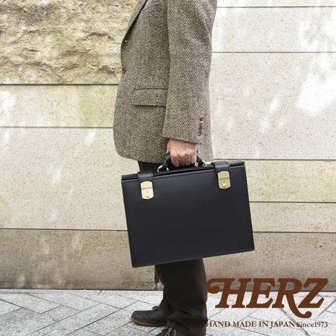 職人手作皮革機師箱 BC-31，黑色光滑牛皮材質，配有金色鎖扣和手柄，適合商務人士。