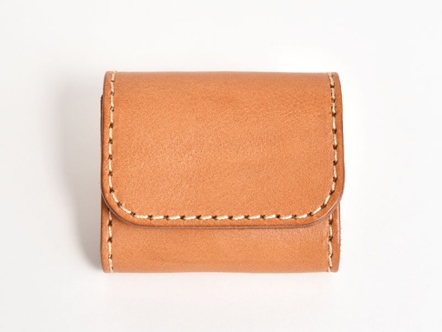 職人手作皮革雙折收納零錢包，採用天然棕色皮革製成，外觀簡約，邊緣有手工縫線裝飾，整體呈現質感。