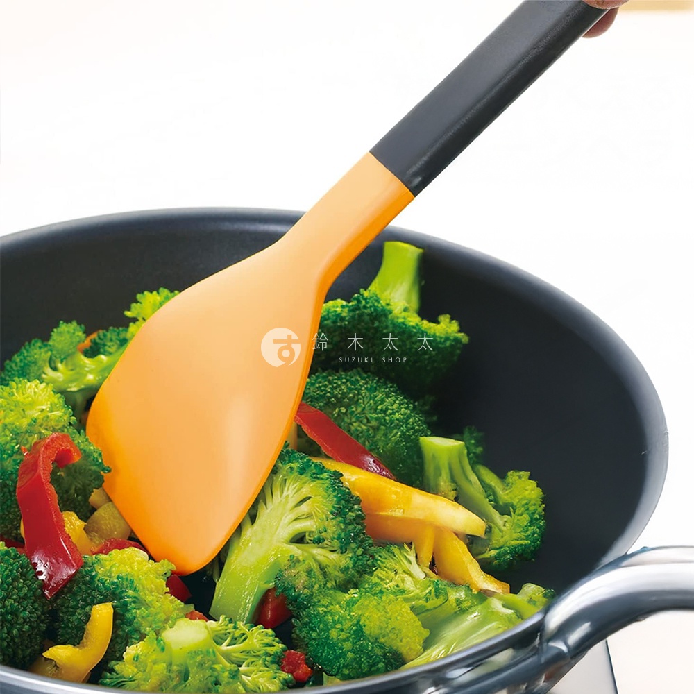 一只橘色鍋鏟正在炒鍋中翻炒西兰花和彩椒