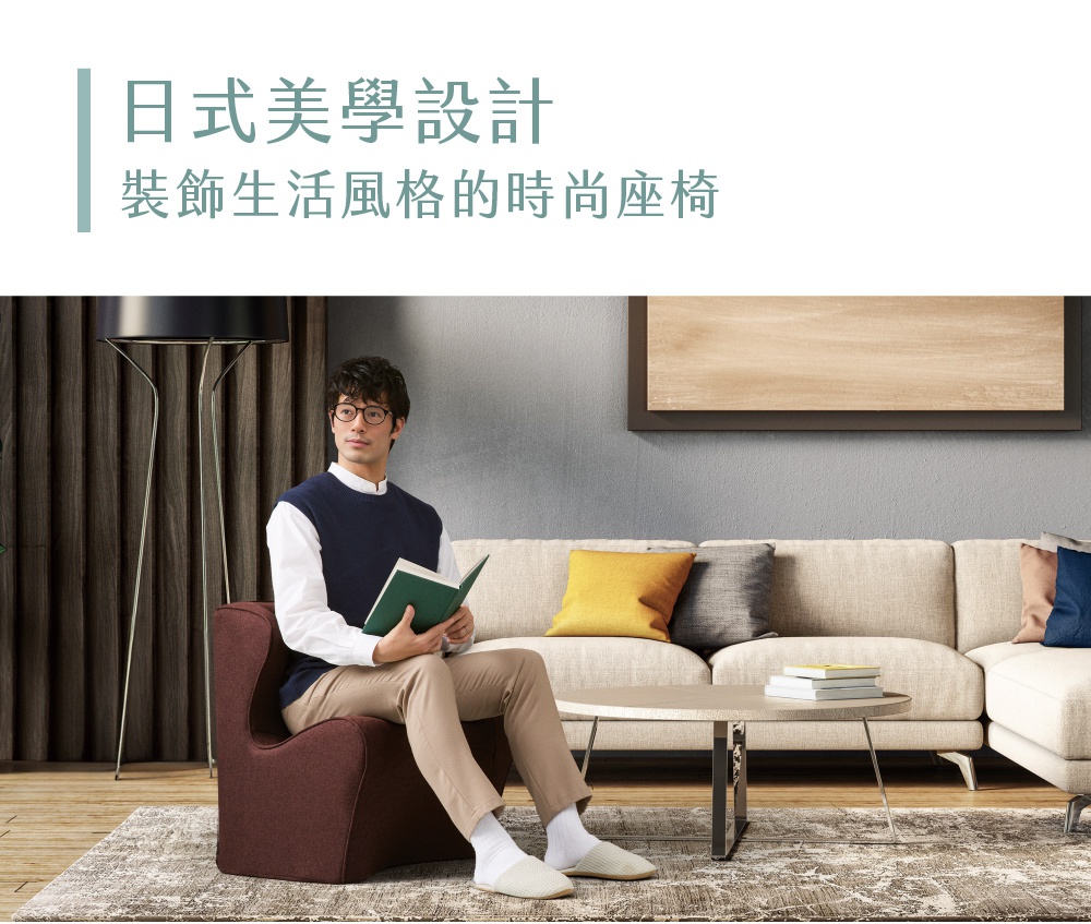 一名男子坐在深紅色布藝調整椅上，手持一本綠色書籍，椅旁有沙發、茶几和地毯。