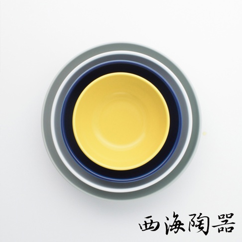 由左至右疊放著四個尺寸遞減的陶瓷深碗，顏色分別為灰、灰藍、深藍、亮黃。