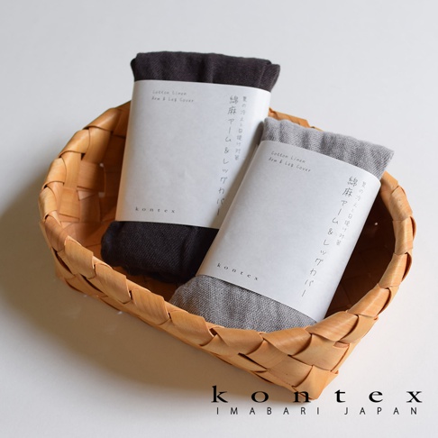 兩個由棉麻混紡製成的袖套，分別為深灰色和淺灰色，皆以白色紙帶包裝，置於編織籃內。