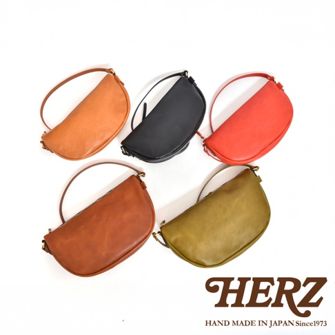 日本HERZ職人手作皮革半圓馬鞍包，五種顏色皮革包排成一列，並標有品牌名稱。