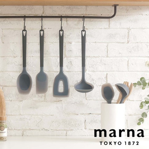 marna TOKYO 1872 品牌下的 quatre ustensiles de cuisine en silicone gris et noir sont accrochés à un support mural.