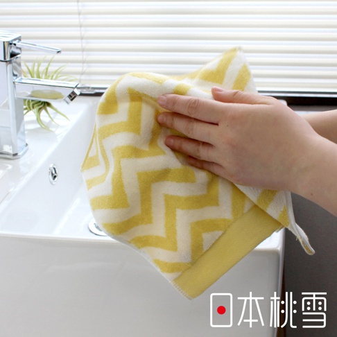 一條今治北歐方巾，採用黃白相間的鋸齒紋設計，材質為柔軟的毛巾布，一隻手正拿著方巾擦拭。