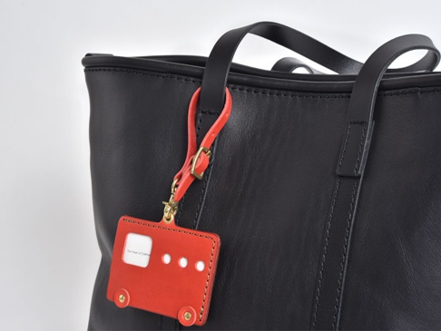 職人手作皮革可調式吊掛帶 (KZ-4)，紅色皮革製成，造型為小巴士，附有金色釦環和可調式掛繩，吊掛於黑色皮革托特包上。