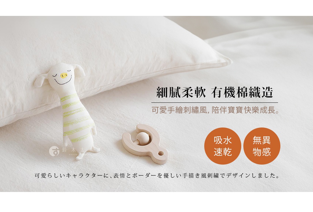 白色柔軟的有機棉毛巾，上面有綠色條紋的可愛小動物玩偶，以及一個木製嬰兒抓握玩偶，皆放置於白色背景上。