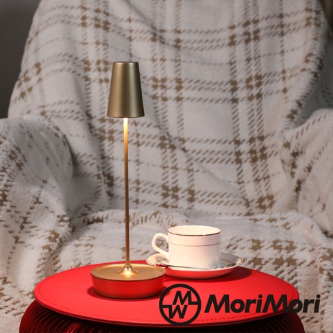 金色金屬復古氛圍燈，燈罩呈圓錐形，細長的燈桿，圓形底座，搭配白色帶金邊的咖啡杯和茶碟，背景為格紋毯子。