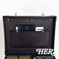 職人手作黑色皮革英倫風便攜手提行李箱，內部結構展示，包含一個平板電腦、兩本文件夾，以及一個皮革置物袋，箱體有金色鎖扣及鉚釘裝飾。