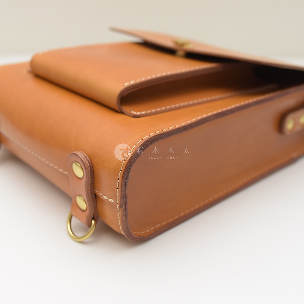 職人手作皮革復古後背包，採用棕色皮革，帶有縫線細節、金屬扣環和側邊固定環。